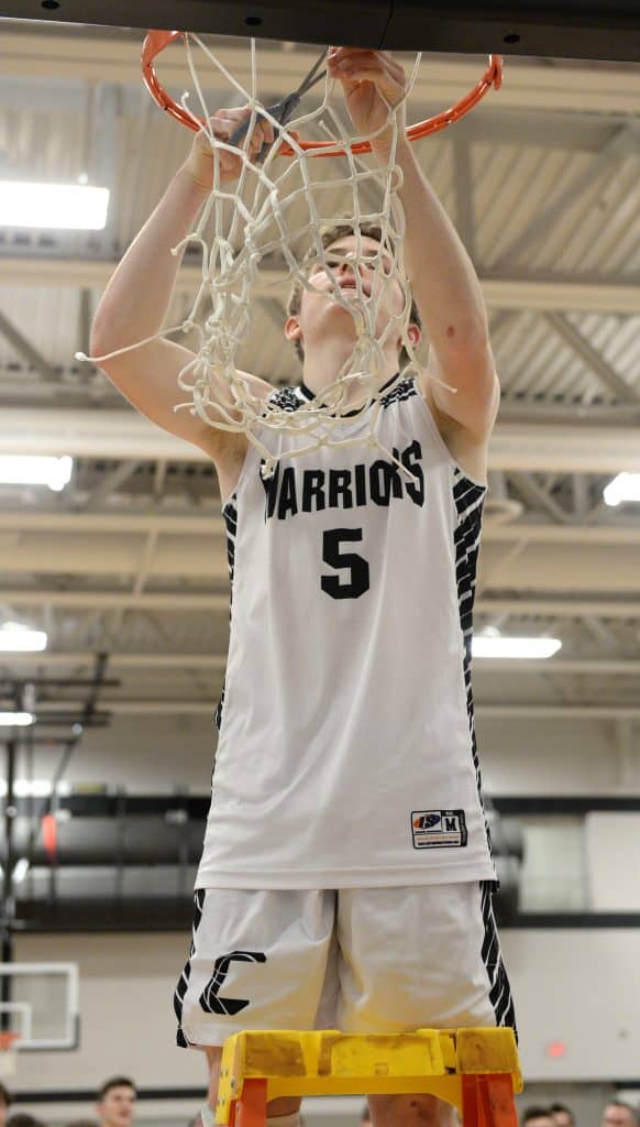 Jimmy Birong, who gave the Warriors a win with a buzzer-beater shot Friday, cuts the net down following the sectional championship game.