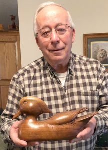 Chuck Huddleston displays a duck he carved from walnut, a piece that required 400 hours to complete.