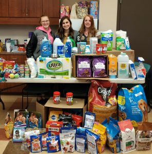 Pictured with the items are (from left): Emily Waggoner and Eva Johnson, members, and high school advisor Sara Cunningham.